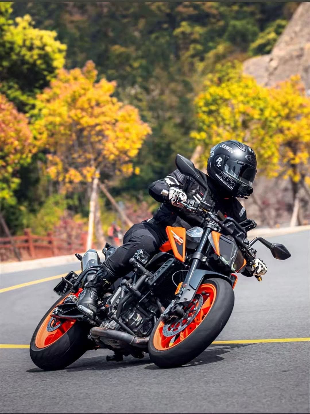 Du Chongyang cornering on an orange motorcycle in full protective gear