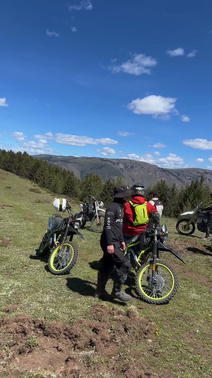 Off-road motorcycles and riders gathered on an open mountain trail
