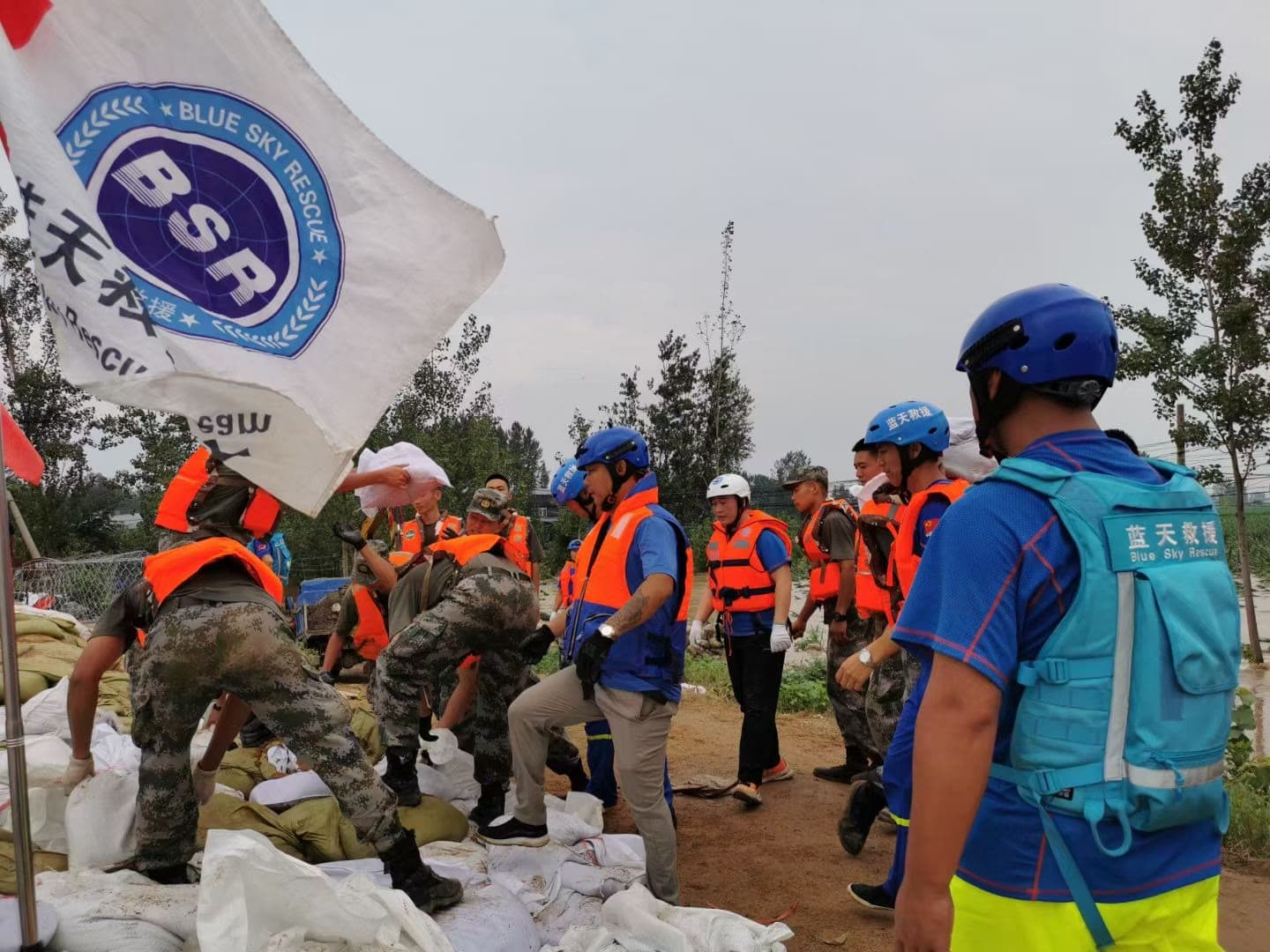 Blue Sky Rescue personnel coordinating beside stacked sandbags