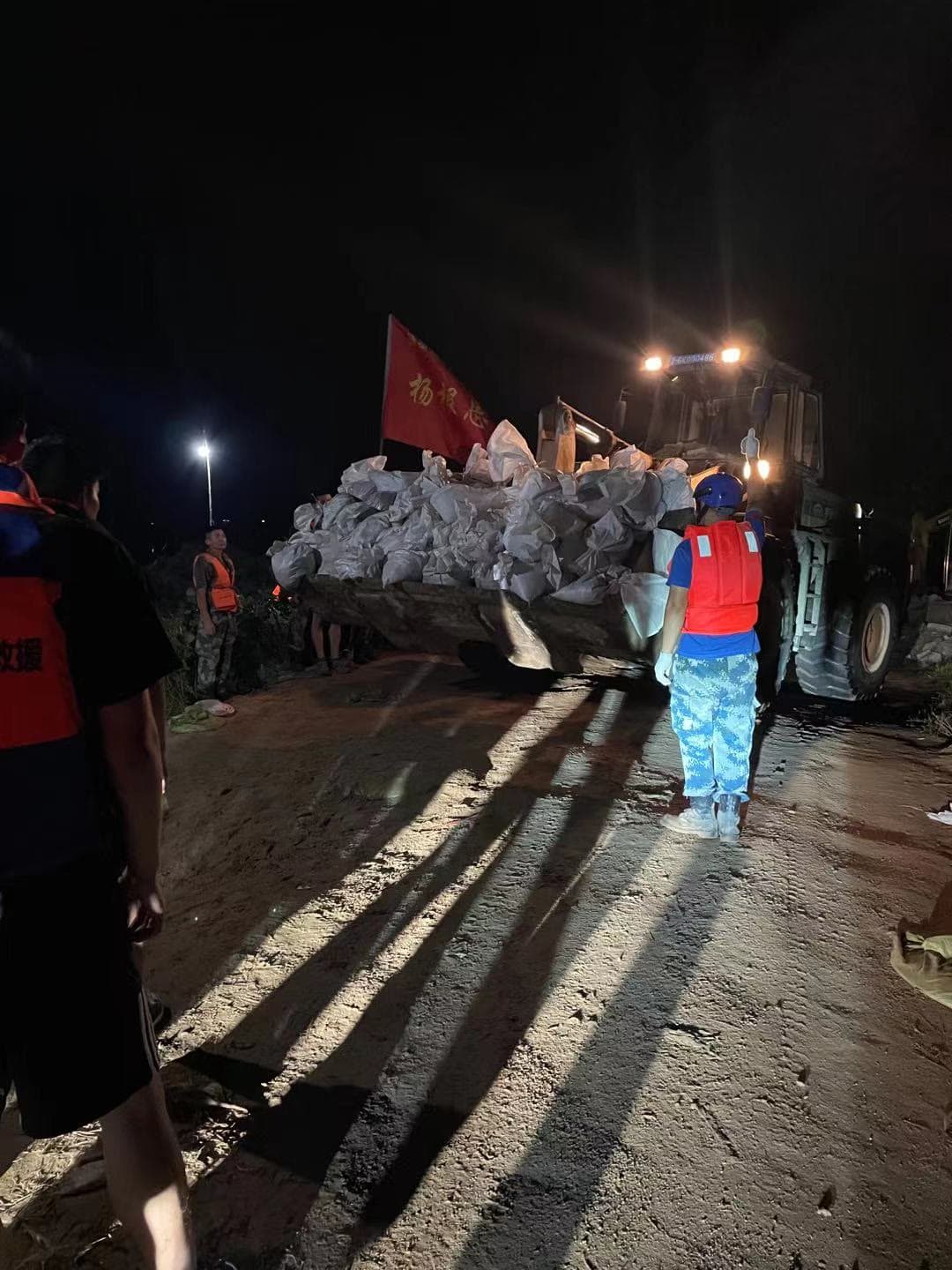 Rescue personnel supporting an overnight sandbag loading operation